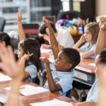children raising hands in class